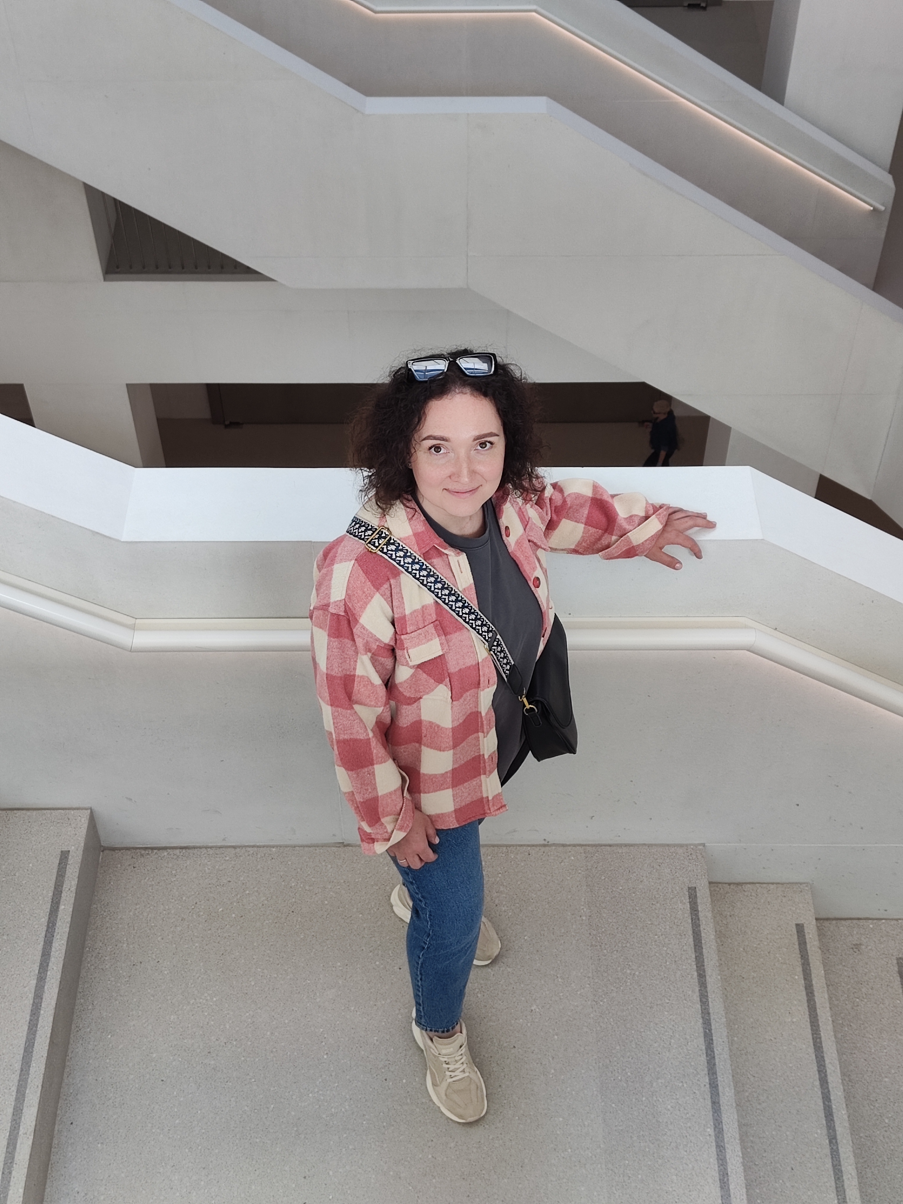 Jeanine White smiling in a red plaid shirt and tortoise shell glasses